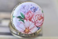 Close up of watercolour floral pocket watch pendant with pink roses and purple blooms