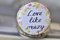 Close-up of the "Love Like Crazy" pocket watch pendant lid with pink and green floral wreath artwork
