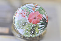 Close-up of hibiscus and tropical foliage design on pocket watch necklace pendant