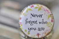 Close-up of the Never forget who you are quote surrounded by watercolour flowers on pocket watch lid