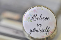 Close-up of pocket watch pendant lid featuring watercolour flowers and the words "Believe in yourself"