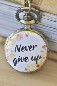 Close-up of Never Give Up pocket watch necklace with floral design on antique bronze case