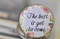 Close up of pocket watch pendant lid with pink floral border and inspirational quote