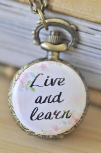 Bronze pocket watch necklace with a floral 'Live and learn' quote design on the front cover