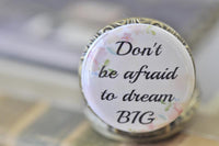 Close-up of pocket watch pendant lid with pastel floral border and dream big quote