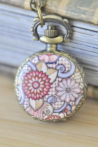 Antique bronze pocket watch necklace with pink and lilac floral swirl design under glass dome