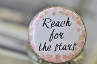 Close-up of Reach for the Stars quote pendant with pink and gold flower border