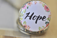 Close-up of Hope pocket watch pendant with pink floral wreath detail