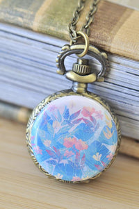 Close-up of bronze pocket watch necklace with soft watercolour floral artwork on the lid