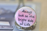 Detail of pink and white pocket watch pendant featuring handwritten bright side of life quote