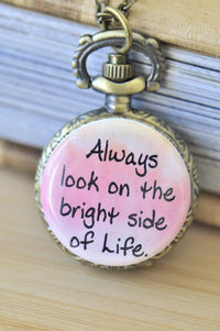 Close-up of pocket watch pendant with pink watercolour background and Always look on the bright side of Life quote
