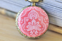 Close-up of pink and blush damask pattern on antique brass pocket watch pendant