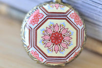 Close-up of oriental lotus flower design on pocket watch pendant in shades of pink, red and cream