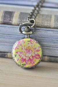 Pocket watch necklace pendant featuring a pink and white dahlia on a yellow background