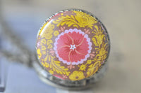 Top-down view of the pink and yellow kaleidoscope flower pocket watch pendant on chain
