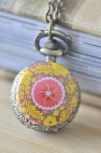 Close-up of oriental kaleidoscope flower pocket watch necklace with pink and yellow floral design