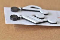 Close-up side view of laser-cut music note earrings showing black and white layers