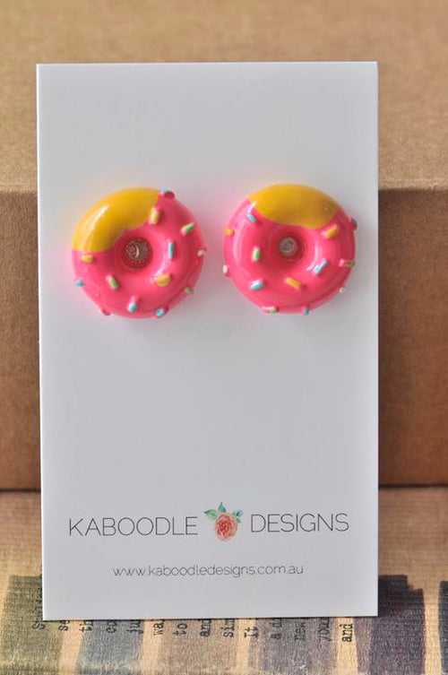 Hot pink resin donut stud earrings with yellow icing and rainbow sprinkles on Kaboodle card