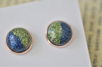 Close-up of glitter resin stud earrings showing blue and green colour split and rose gold frame