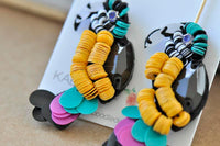 Close-up of sequin toucan earring detail with black gem eye and teal, pink and black tail sequins