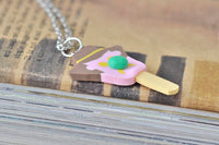 Ice cream pendant necklace laid flat showing full charm shape and cream stick base
