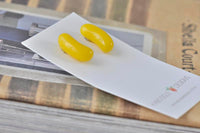 Pair of glossy yellow jelly bean earrings shown at an angle, side by side