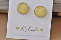 Pair of round sunshine yellow stud earrings with glossy finish on Kaboodle earring card