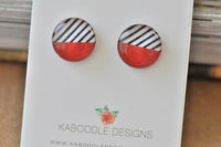 Round stud earrings with black and white diagonal stripes over solid red, shown on Kaboodle Designs card