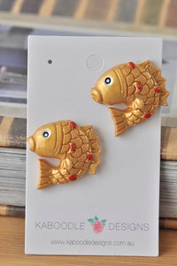 Pair of gold resin goldfish stud earrings with red dot detail on a Kaboodle Designs card