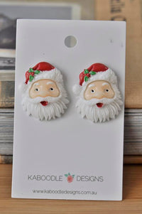Pair of resin Santa Claus face stud earrings on a Kaboodle Designs backing card