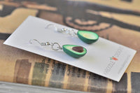 Pair of avocado drop earrings laid across Kaboodle Designs backing card