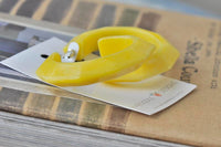 Yellow acrylic hoop earrings resting on their backing card, angled view
