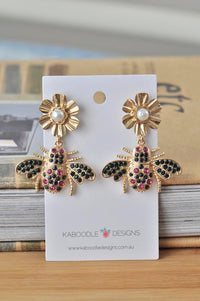 Gold-tone rhinestone bee drop earrings with pearl flower studs on Kaboodle Designs card