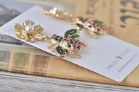 Overhead view of bee and flower earrings on display card resting on books