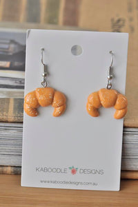 Pair of golden resin croissant drop earrings on a Kaboodle Designs card