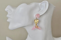 Gold glitter mermaid tail earring with pink fin shown worn on ear