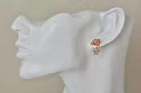 Saturn bead earring with gold star charm shown worn on ear, close-up angle