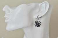 Single black spider earring worn on ear, shown in profile on mannequin head