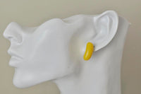 Yellow jelly bean stud earring worn on ear, close-up profile view
