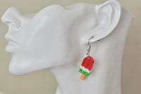 Close-up of single watermelon popsicle earring worn on ear, showing ribbed resin texture