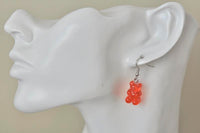Close-up of red gummy bear earring worn on ear showing translucent resin finish