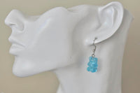Blue gummy bear earring shown worn on ear for scale