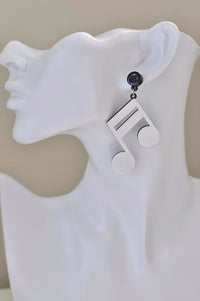 White music note earring worn on a mannequin ear against a plain background