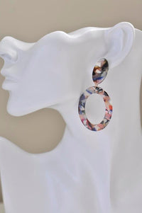 Tortoiseshell resin oval earring worn on ear, showing open hoop drop