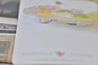 Close-up angled view of the biscuit brooch showing glossy acrylic finish and layered icing detail
