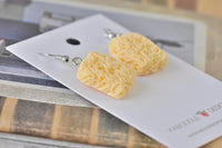 Ramen noodle block earrings laid flat on display card, side angle view