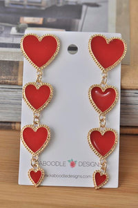 Four red enamel heart drop earrings with gold trim on Kaboodle Designs card, front view