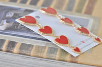 Close-up of red enamel hearts with beaded gold trim linked together on display card