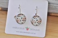 Round boho floral dangle earrings with peach and cream flower print on silver-tone hooks, shown on jewellery card