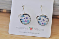 Round boho flower dangle earrings with purple and blue floral design on striped background, shown on Kaboodle card